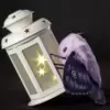 Purple moth plush art doll clinging to a glowing white lantern with star cutouts, dark background
