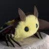 Close-up of handmade moth doll with yellow fluffy face and black feathered antennae