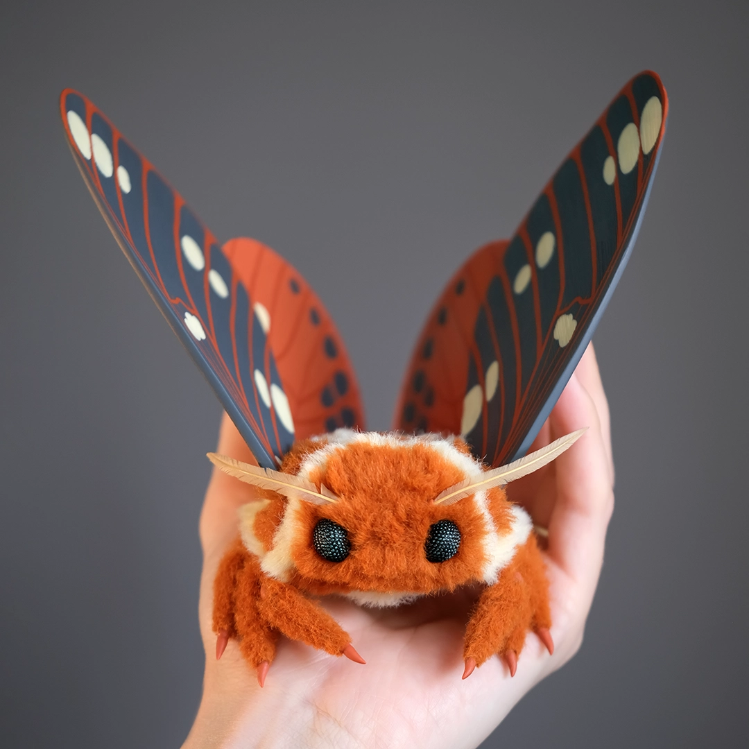 Handmade Regal Moth plush doll with sculpted clay wings, shown resting in an open palm