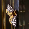 Yellow Garden Tiger Moth doll attached to black textured surface, with yellow vertical threads beside it: brown-and-yellow faux fur, polymer clay wings.