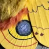 Close-up of the golden-yellow Io Moth art doll showing its textured eye and patterned wing