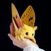Handmade Io Moth art doll with golden-yellow wings held in a hand