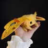 Handcrafted golden-yellow Io moth doll held in hand.
